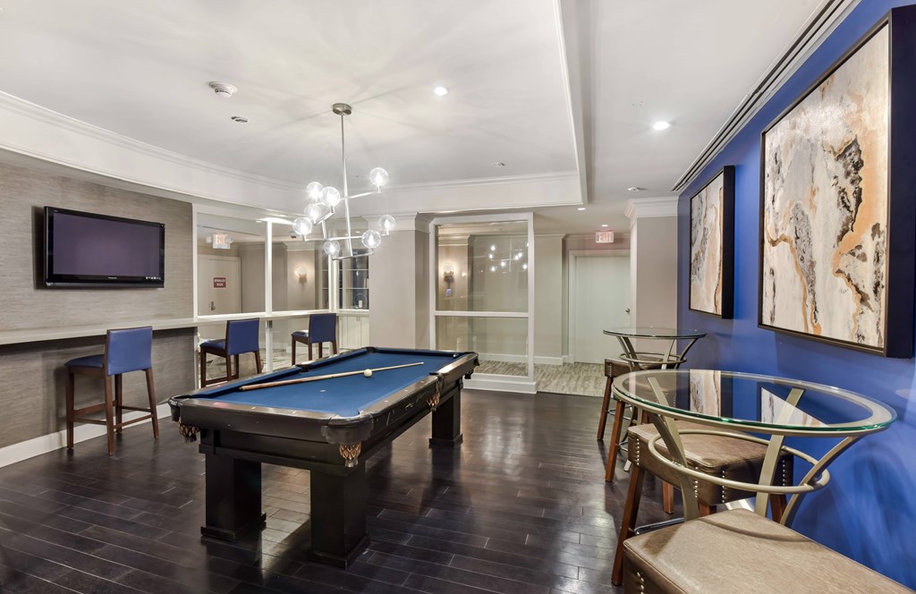 A room with a pool table and chairs.