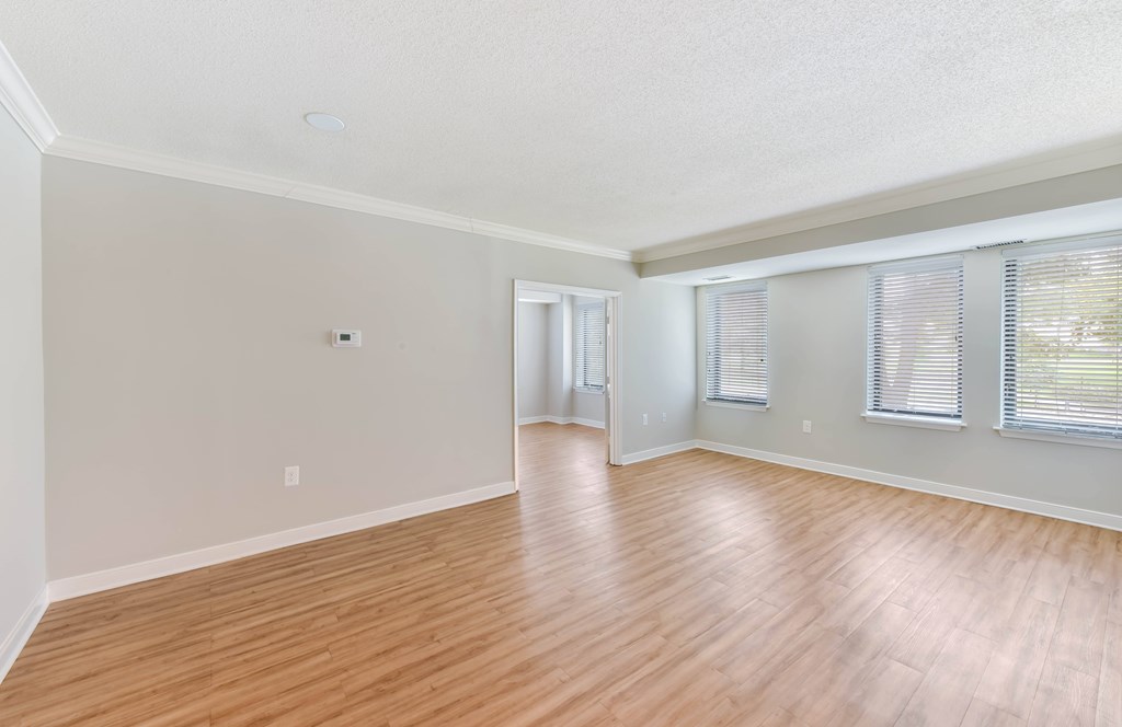 A room with wooden flooring and a window with blinds.
