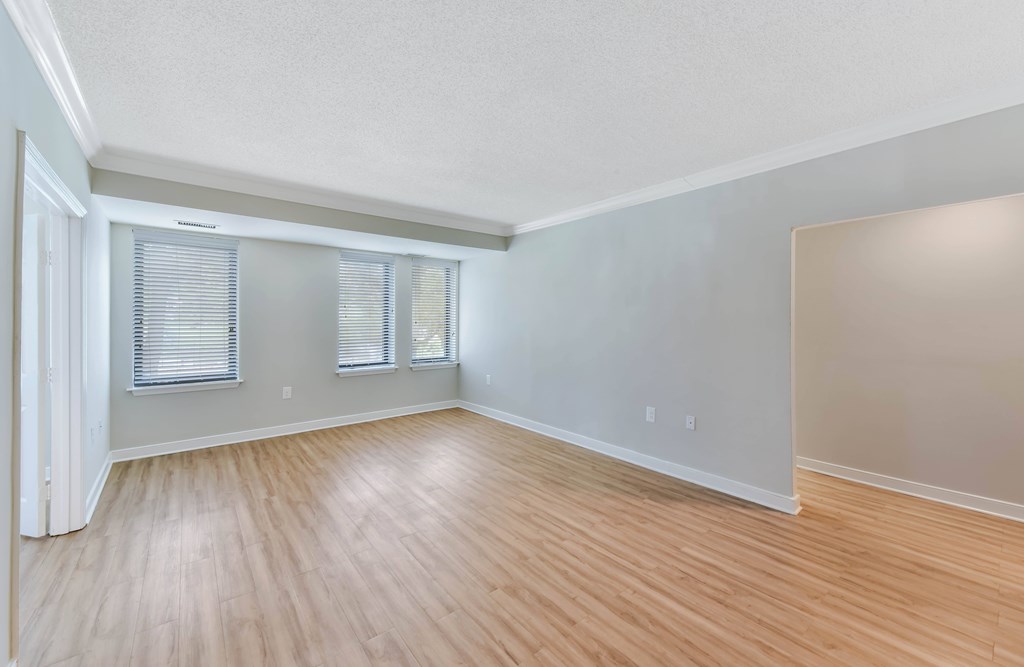 A room with wooden flooring and a window with blinds.