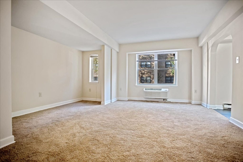 an empty living room with a window and carpet