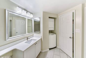 a bathroom with a sink and a mirror and a door at The Saratoga Apartments, Washington, DC, 20008