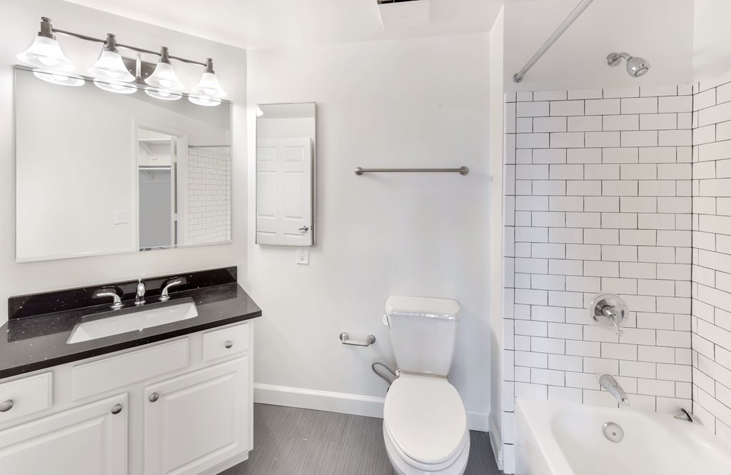 A white toilet sits in a bathroom next to a sink and a bathtub.
