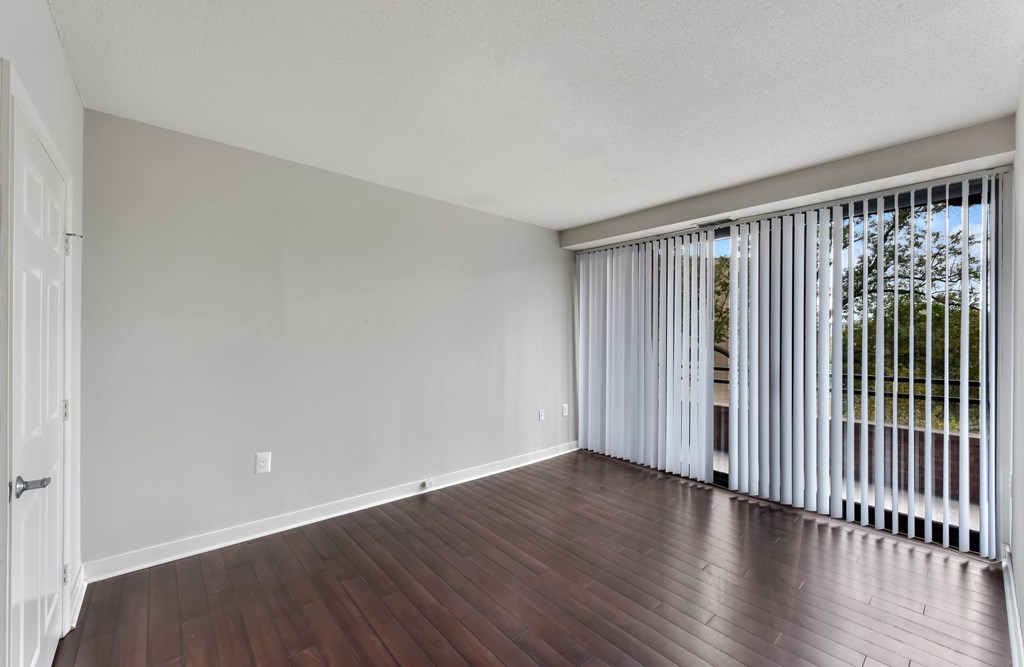 A room with a white door and a window with white blinds.