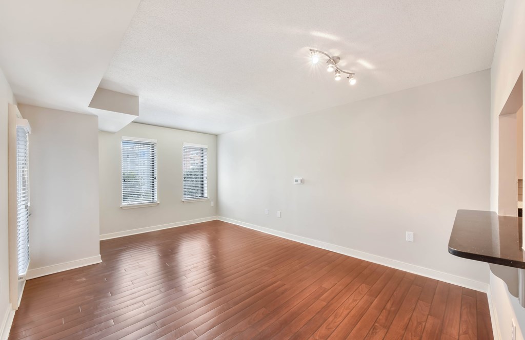 A room with wooden flooring and a window with blinds.
