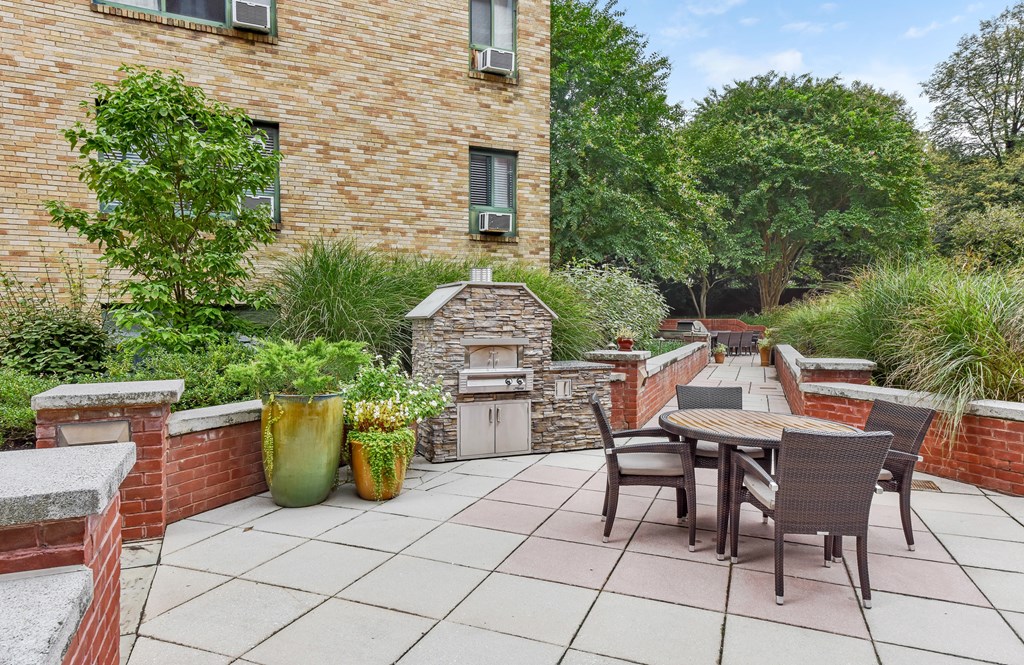 A patio with a table and chairs is surrounded by a brick wall and has a fireplace.