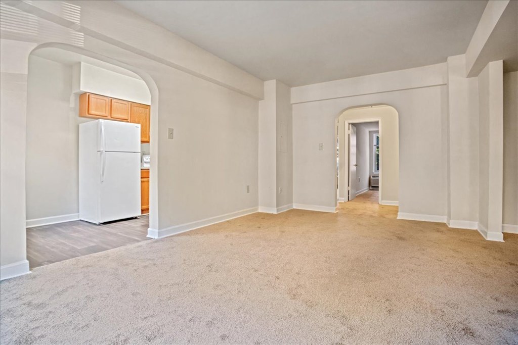 a renovated living room with a kitchen with a refrigerator