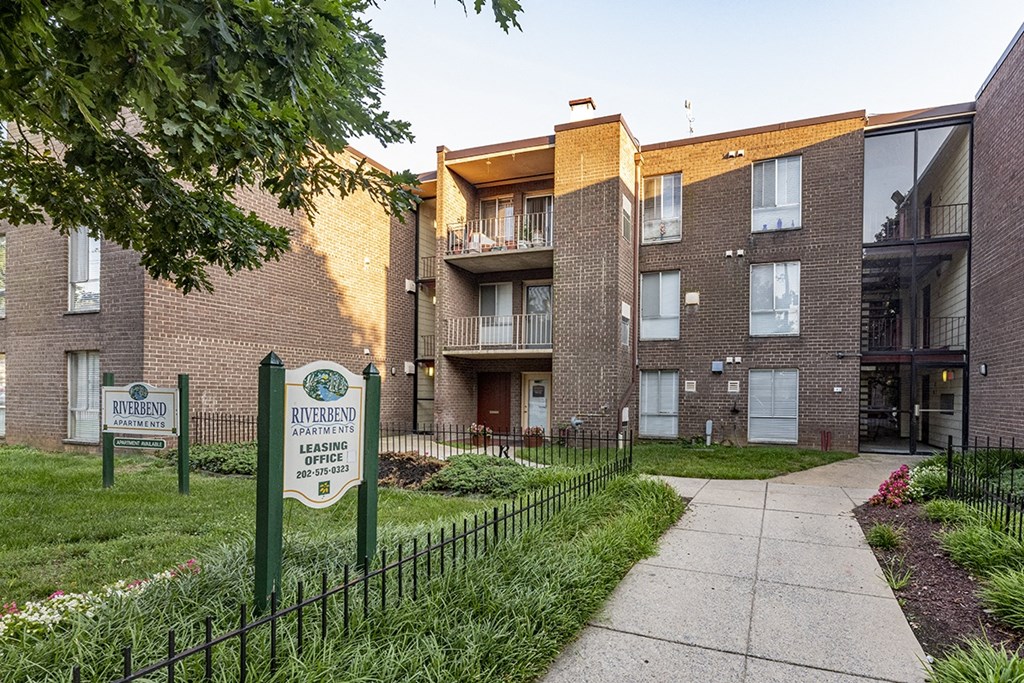 an apartment building with a sidewalk, fence and a sign in front