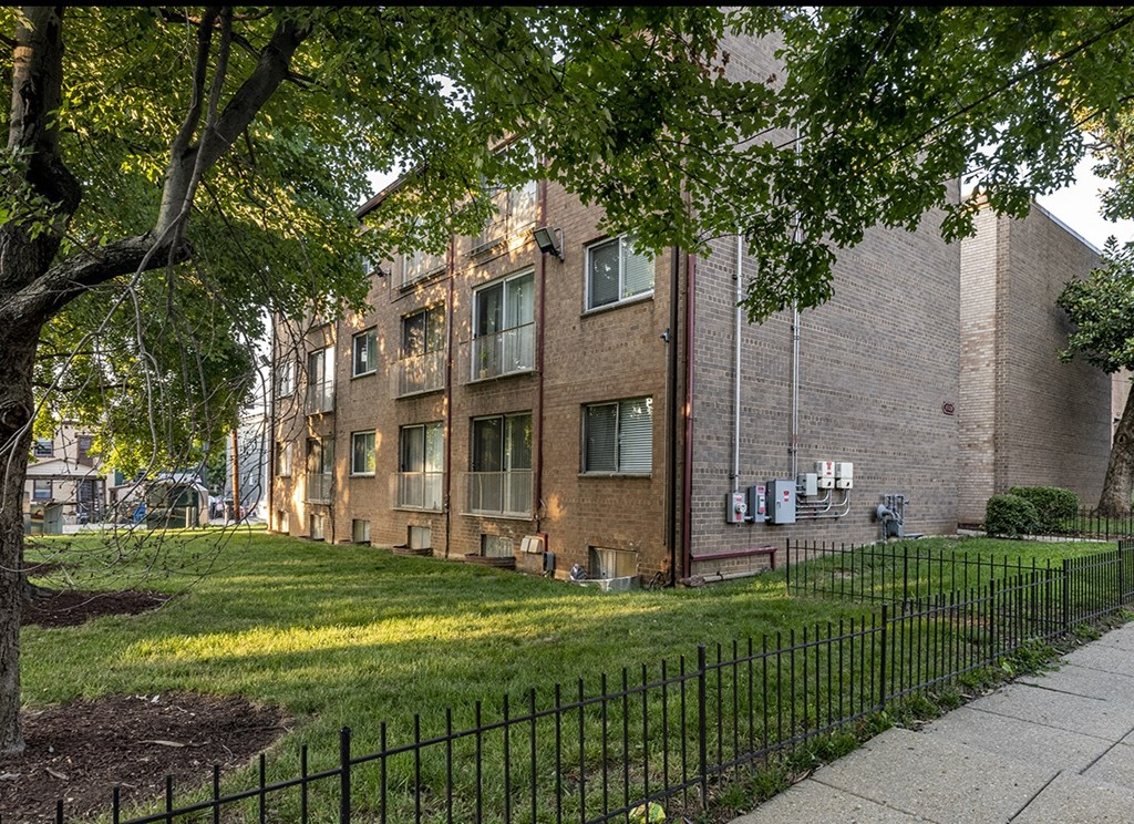 a brick building with a yard and a fence