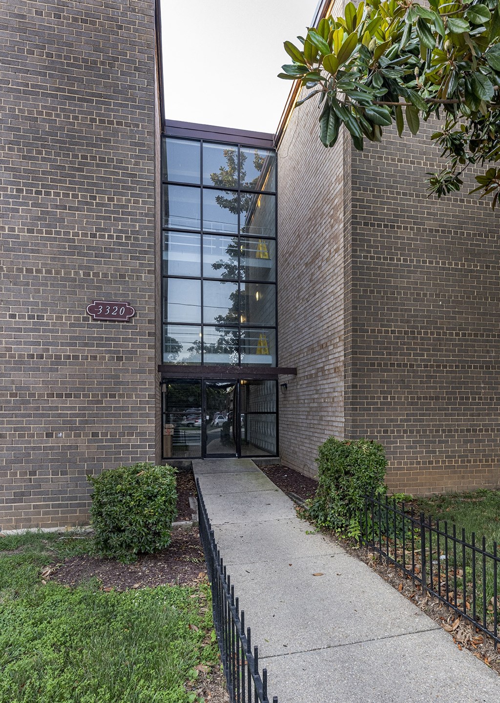 the front entrance of a brick building with a sidewalk and a glass door