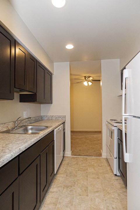 a kitchen with dark cabinets and a white refrigerator and a sink