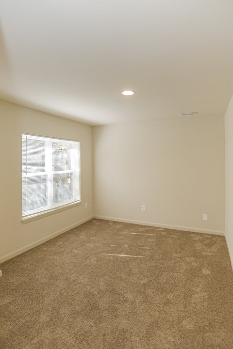an empty living room with carpet and a window