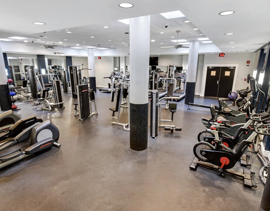A gym with a variety of equipment including treadmills, weights, and exercise machines.