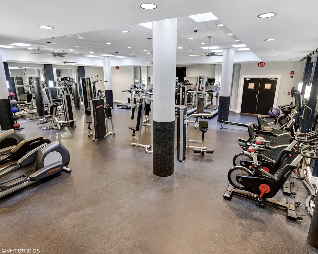 A gym with a variety of equipment including treadmills, weights, and exercise machines.