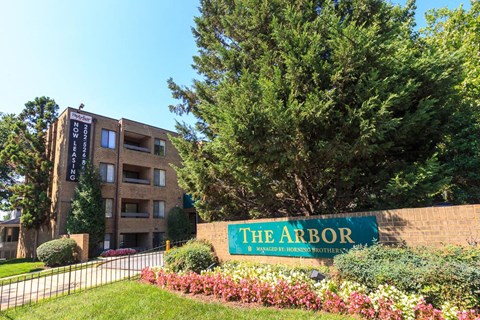 a large brick building with a sign for the arbor in front of a tree