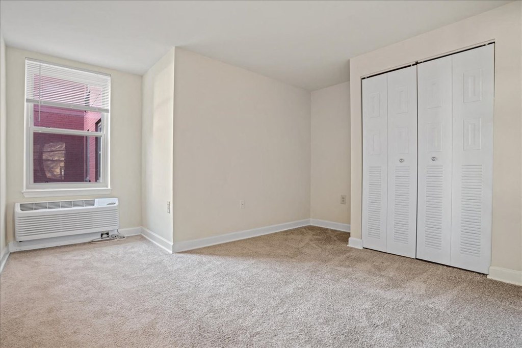 a bedroom with white closet doors and a window