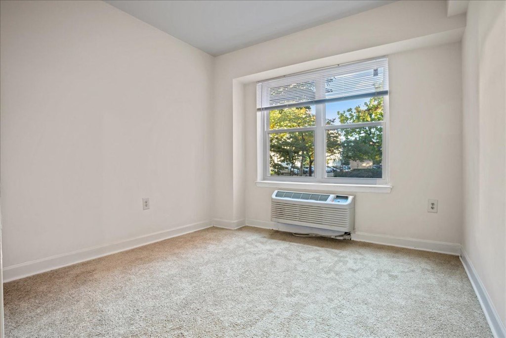 an empty room with a window and an air conditioner