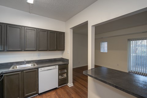 A kitchen with dark brown cabinets and a white dishwasher.