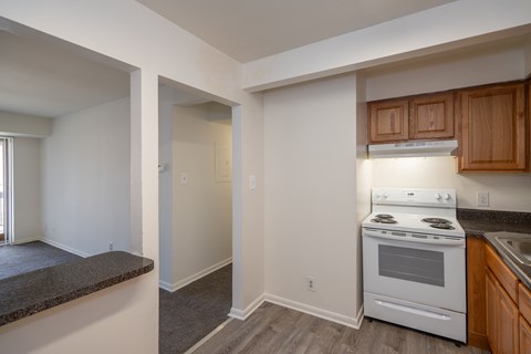 A kitchen with a white stove top oven and wooden cabinets.