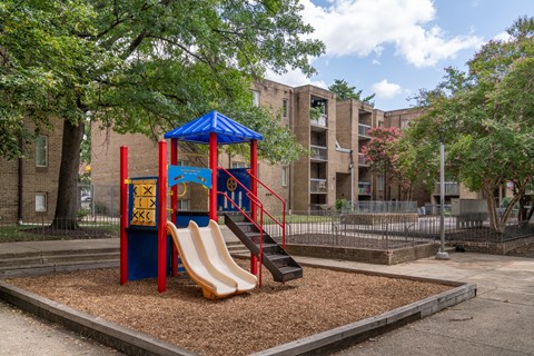 A playground with a blue and red structure and a yellow slide.