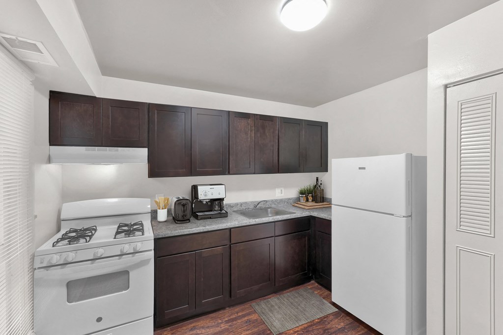 a kitchen with white appliances and brown cabinets and a refrigerator