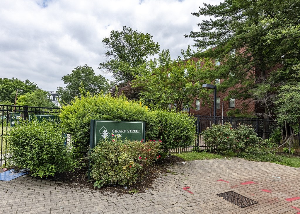 a sign in front of the community with bushes and trees