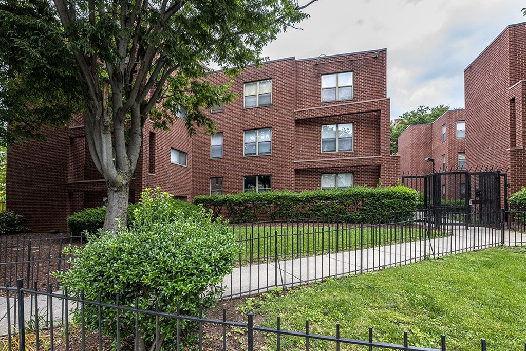 an apartment building with a yard and a wrought iron fence
