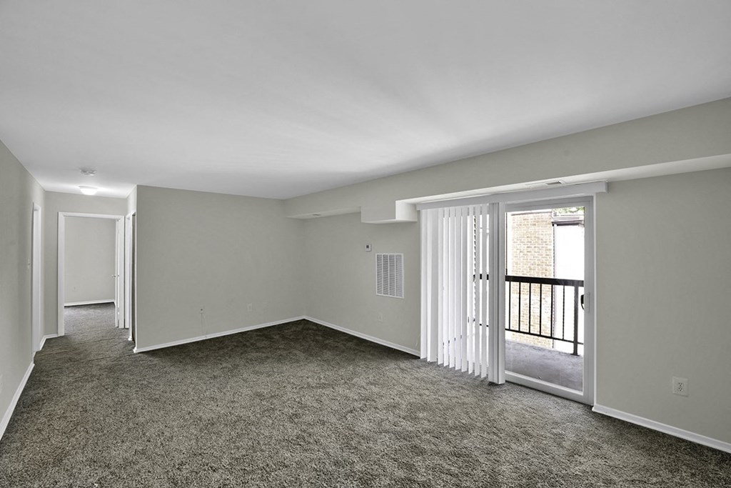 an empty living room with a door to a balcony