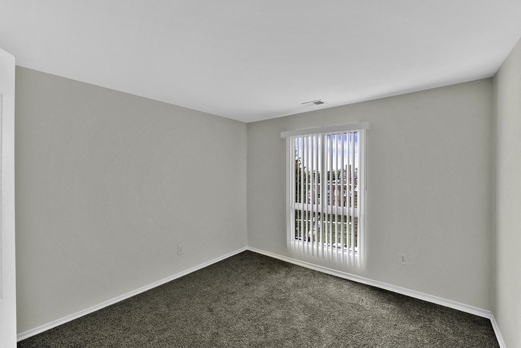 a spacious living room with a large window and carpeting