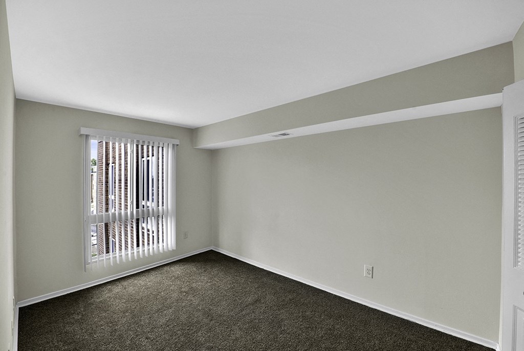 the spacious living room of an apartment with a large window