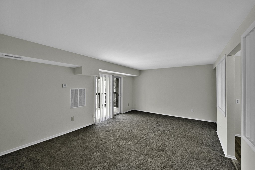 an empty living room with gray carpet and white walls