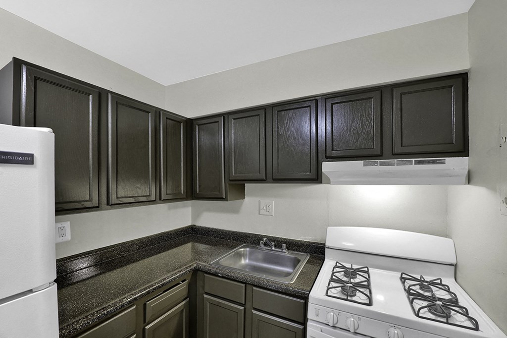 an empty kitchen with black cabinets and white appliances