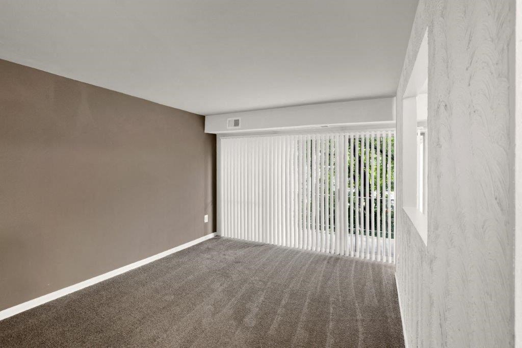 an empty living room with white blinds and a window