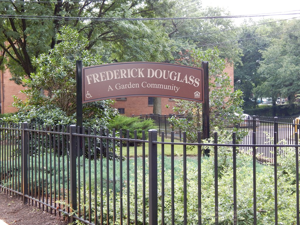 a sign forfrederick douglass a garden community behind a fence