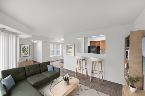 A living room with a green couch, a coffee table, and a bar area with stools.