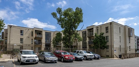 a row of apartment buildings with cars parked in a parking lot
