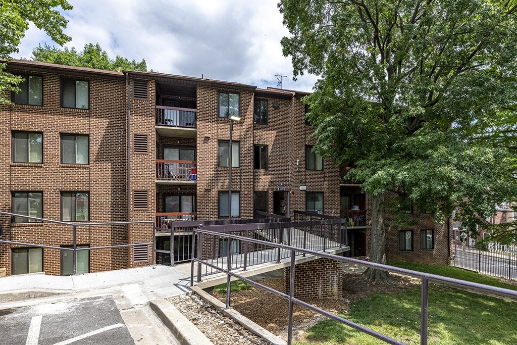 a brick apartment building with stairs and a tree in front of it