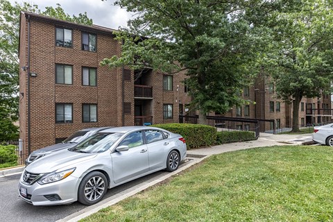 a silver car parked in front of a brick apartment building