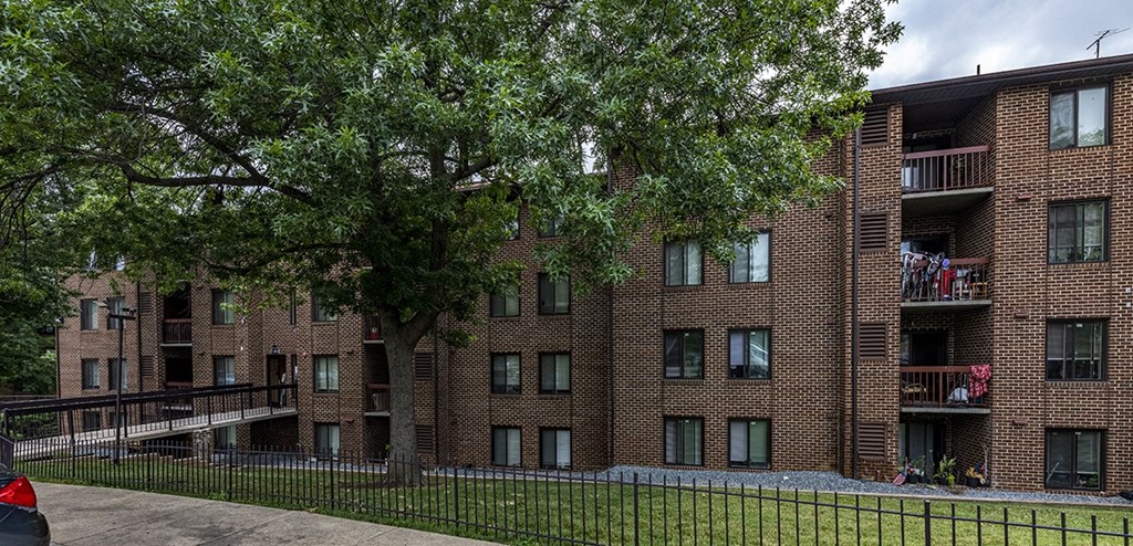 a red brick apartment building with a tree in the yard