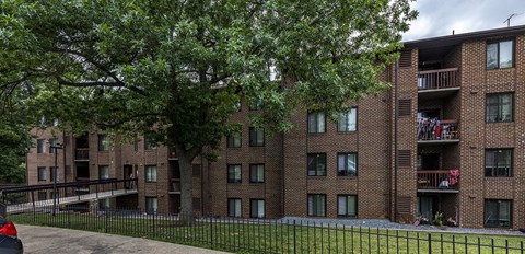 a red brick apartment building with a tree in the yard