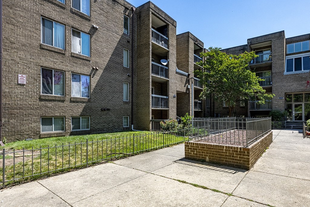 a brick apartment building with a yard and a fence