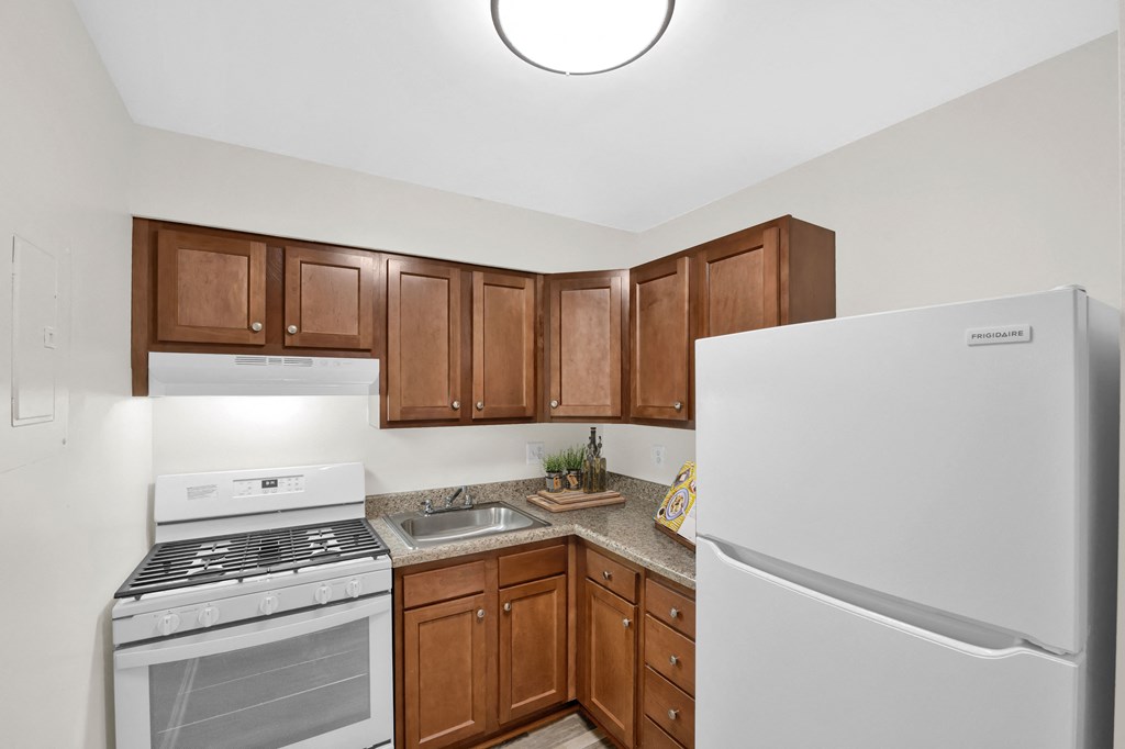 a kitchen with white appliances and brown cabinets and a refrigerator