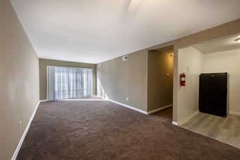 an empty living room with a large window and a door to a balcony