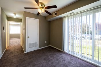 an empty living room with a large window and a ceiling fan