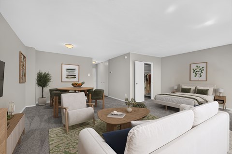 A living room with a white couch, a coffee table, and a bed in the background.