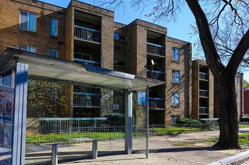an apartment building with a bus stop in front of it