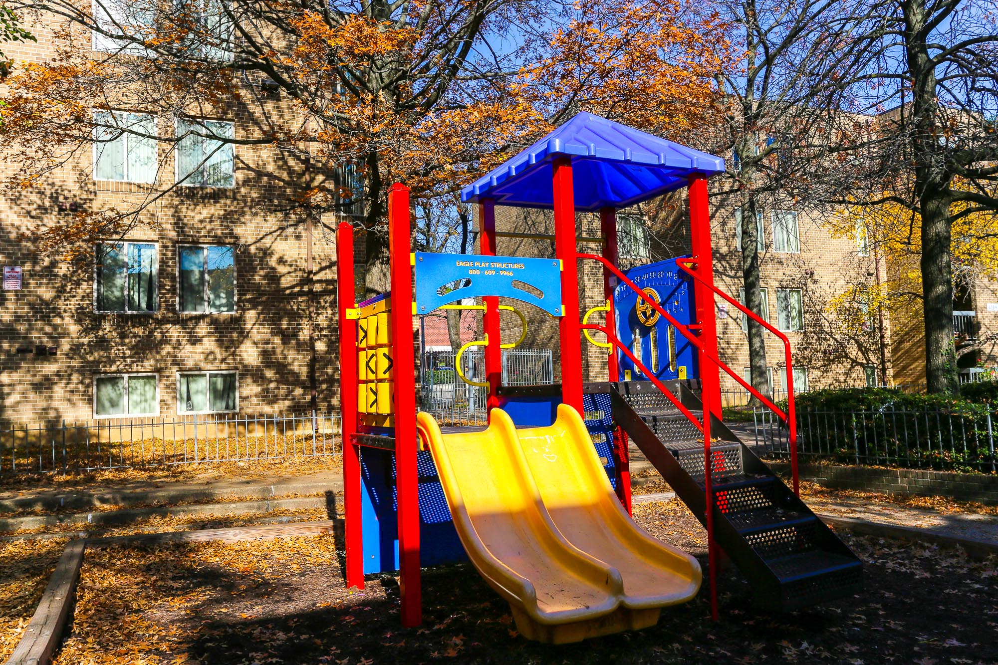 a playground with slides and a swing set in front of an apartment building