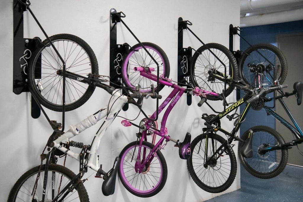 A collection of bicycles are hanging on a wall.