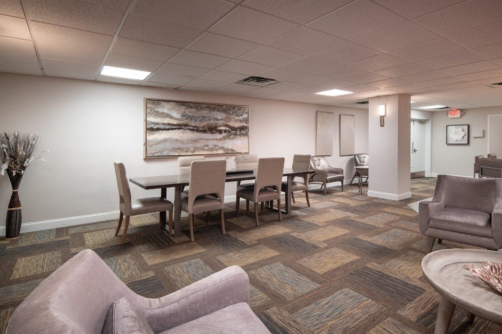 A room with a table and chairs and a painting on the wall.