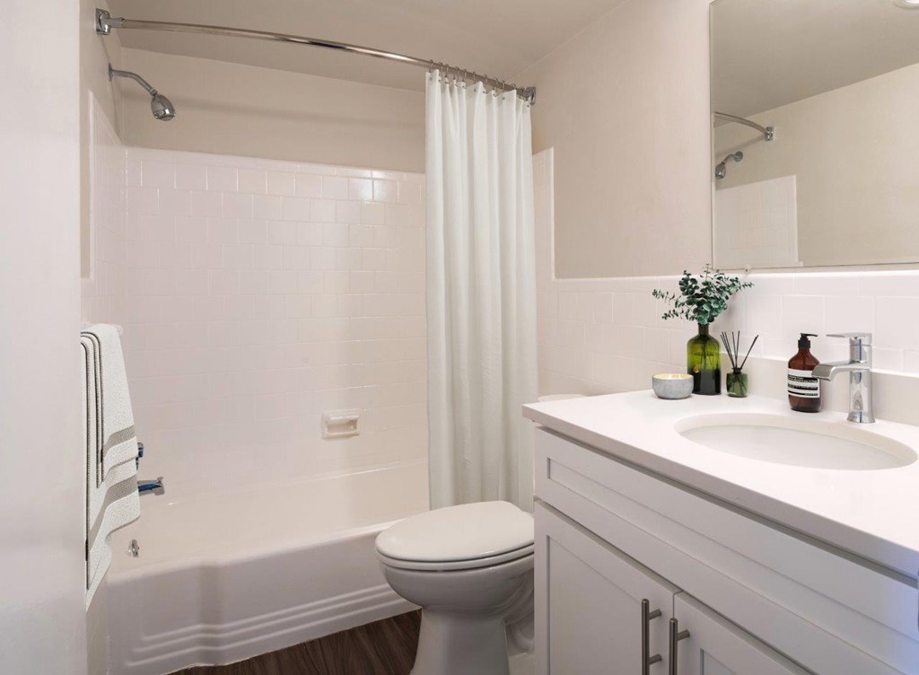 A white bathroom with a toilet, sink, and shower.