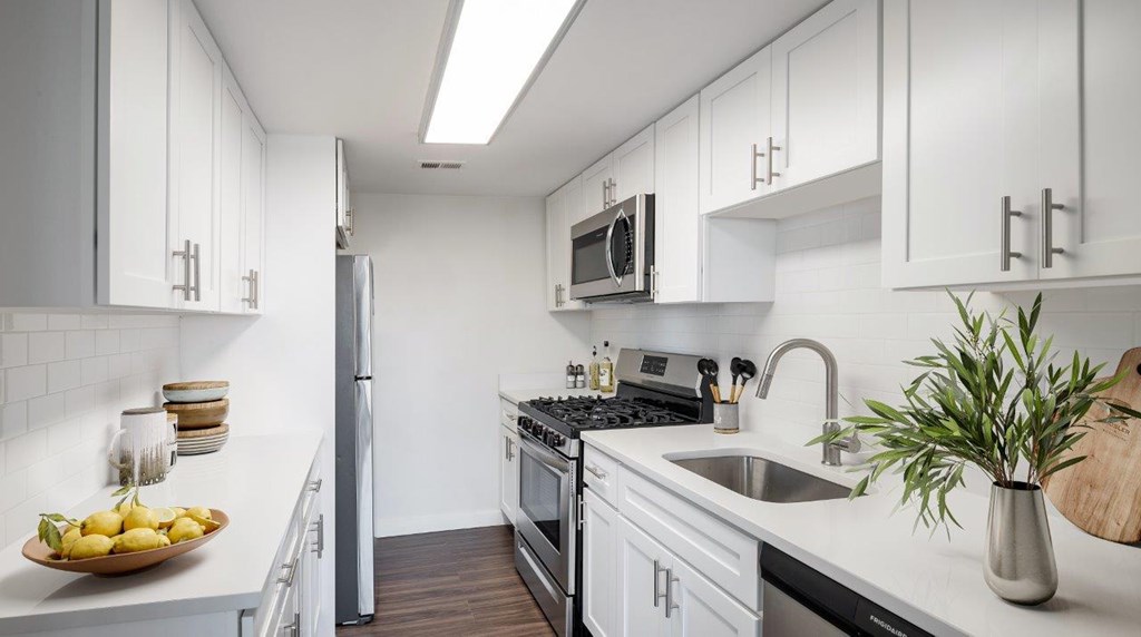 A kitchen with white cabinets and a stainless steel refrigerator.